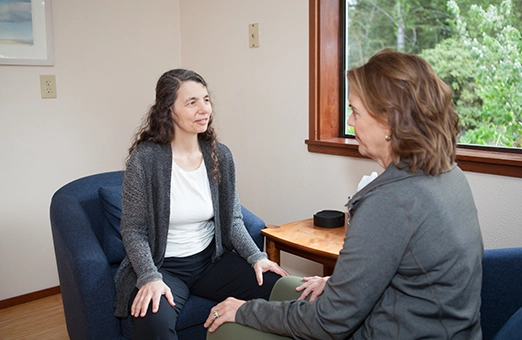 Laura Yedwab, a Kirkland Feldenkrais practitioner, seated and talking with a client during a consultation.