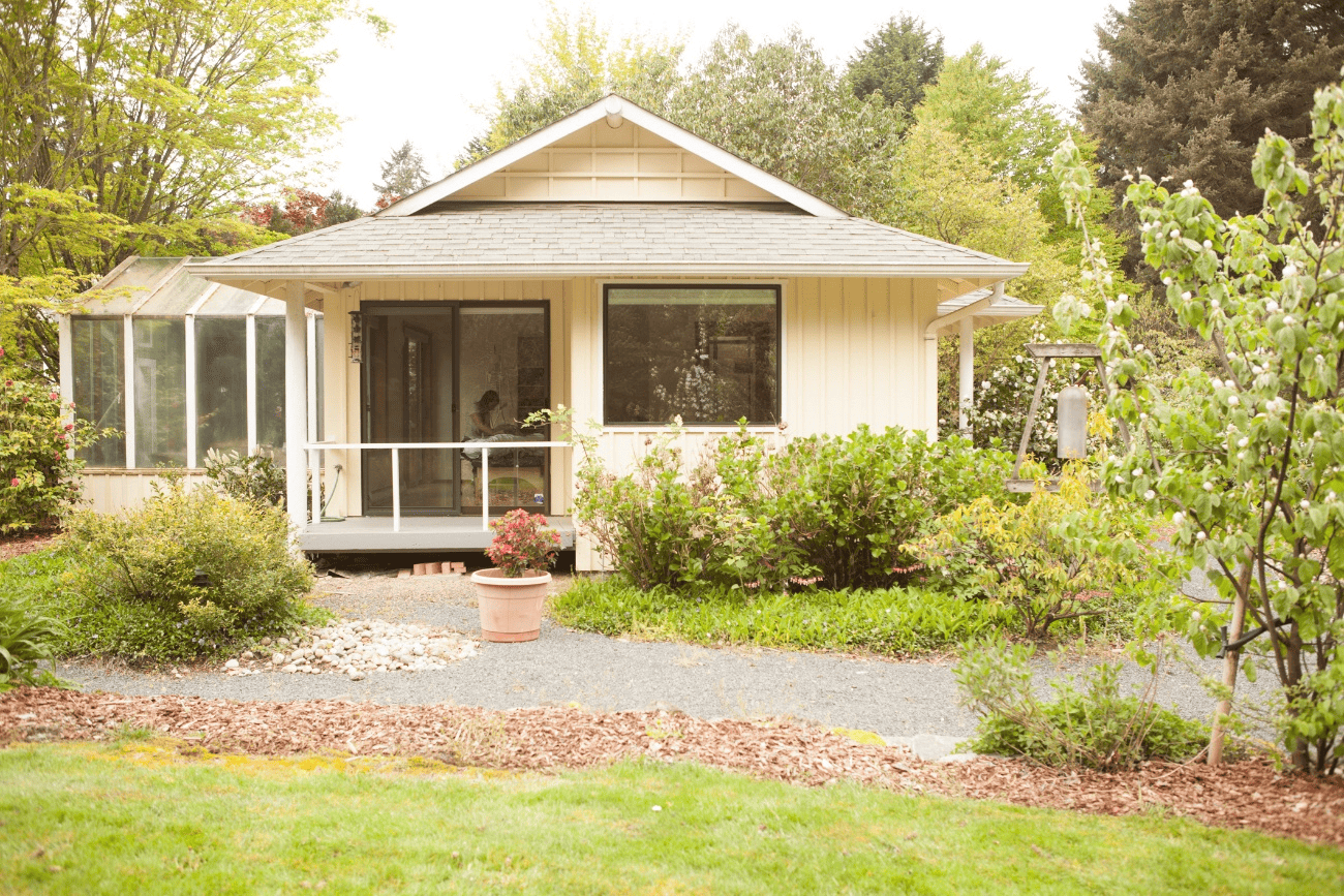 The exterior of Laura Yedwab's Feldenkrais studio in Kirkland, a yellow cottage with garden beds and a gravel path